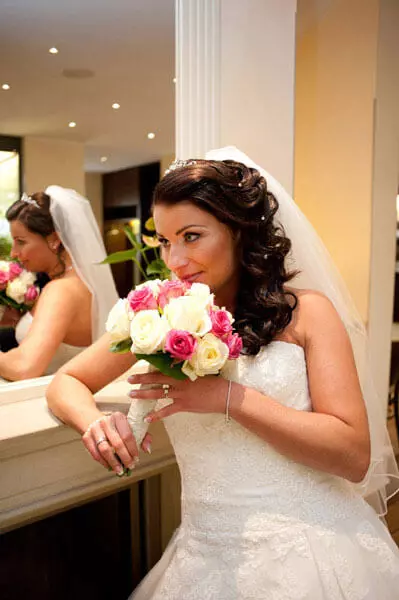 la novia con su ramo de flores frente al espejo