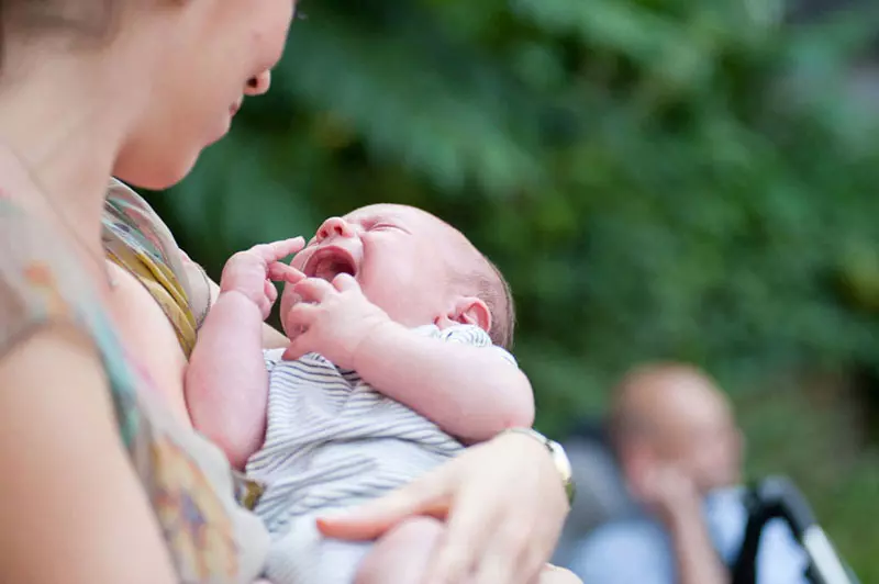 fotógrafo de bodas en Madrid, madre con un niño llorando en su brazo